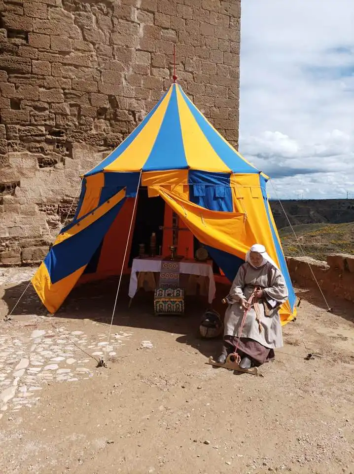 Mujer en campamento de reconstrucción histórica medieval junto a una tienda de campaña