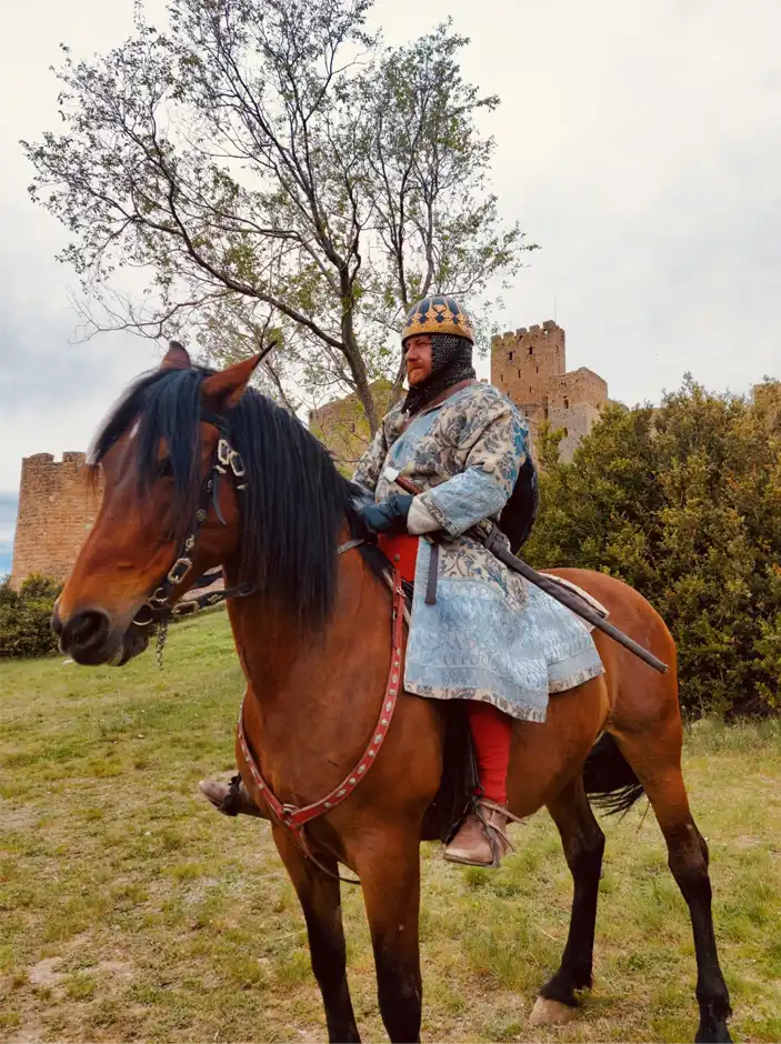Reconstrucción histórica medieval con jinete a caballo frente a una fortificación